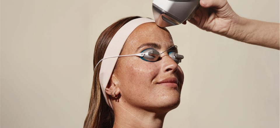 Paciente recebendo tratamento facial a laser, usando óculos de proteção